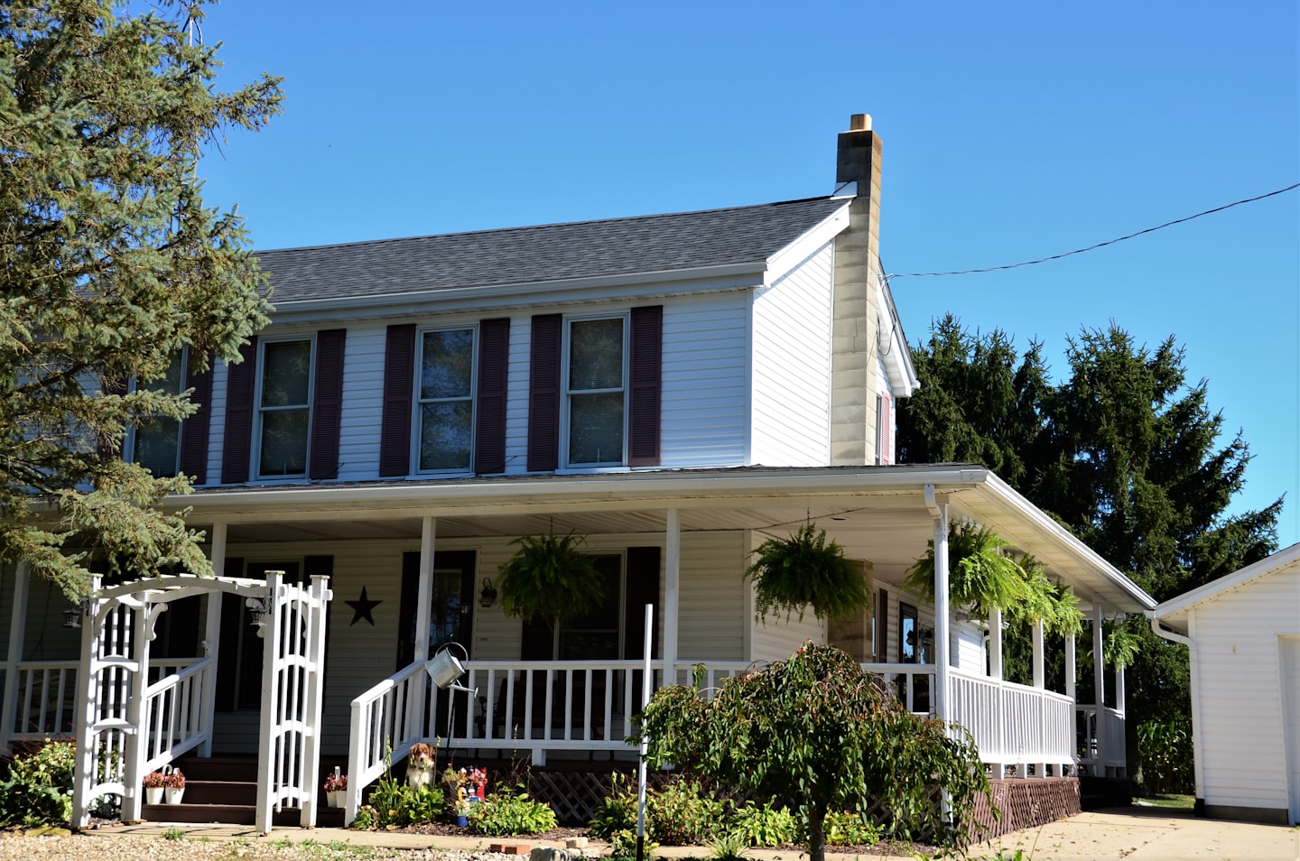 A two-story home with a large covered front porch and a white picket railing
